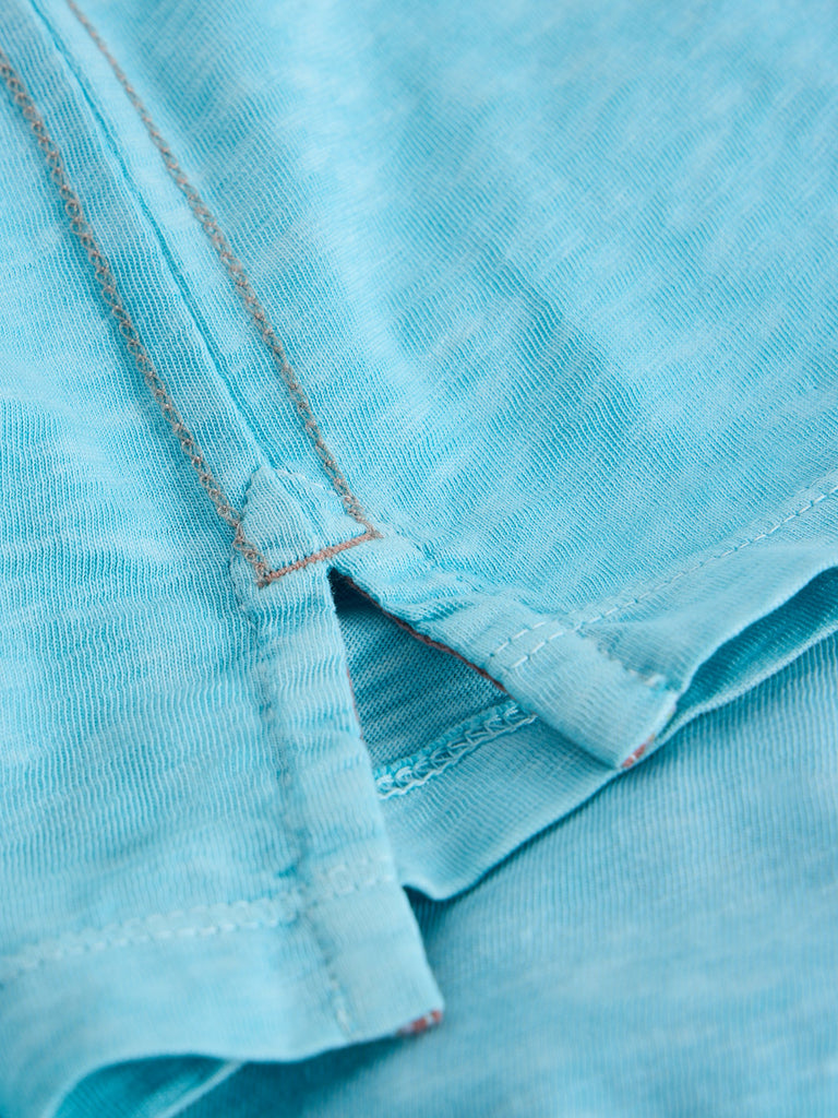 Close-up of light blue fabric with detailed stitching, showing texture and a side seam.