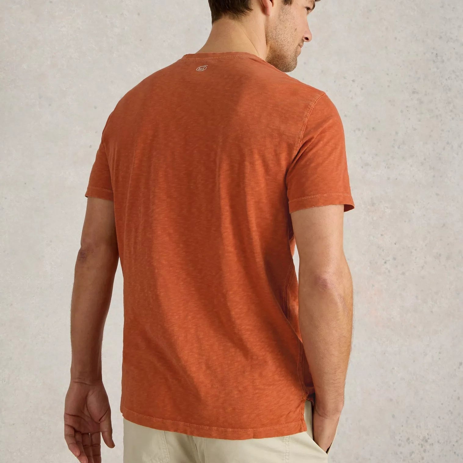 Burnt orange short-sleeve crew neck t-shirt, shown from the back, featuring a small, subtle logo on the upper back.