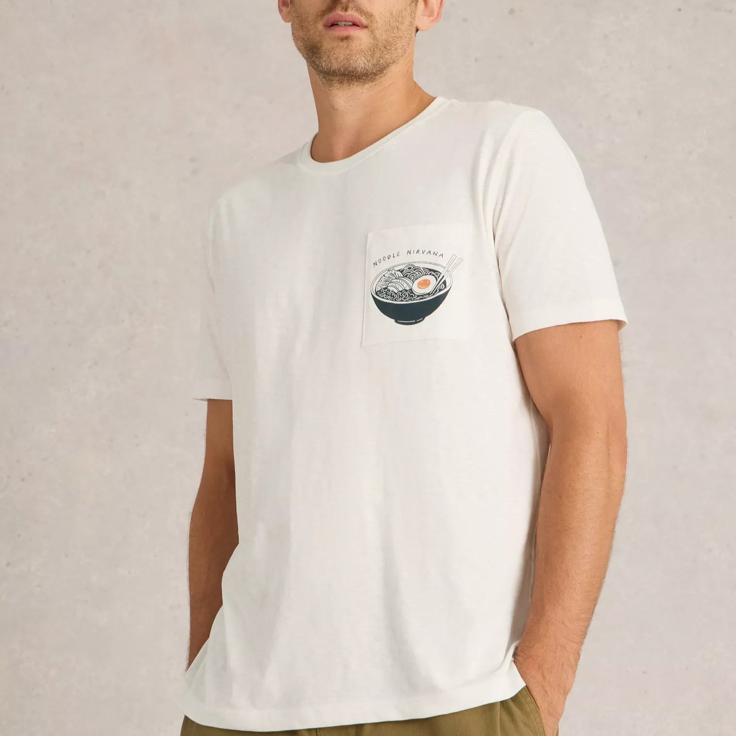 Off-white crew neck t-shirt with a pocket featuring a graphic illustration of a bowl of ramen noodles.