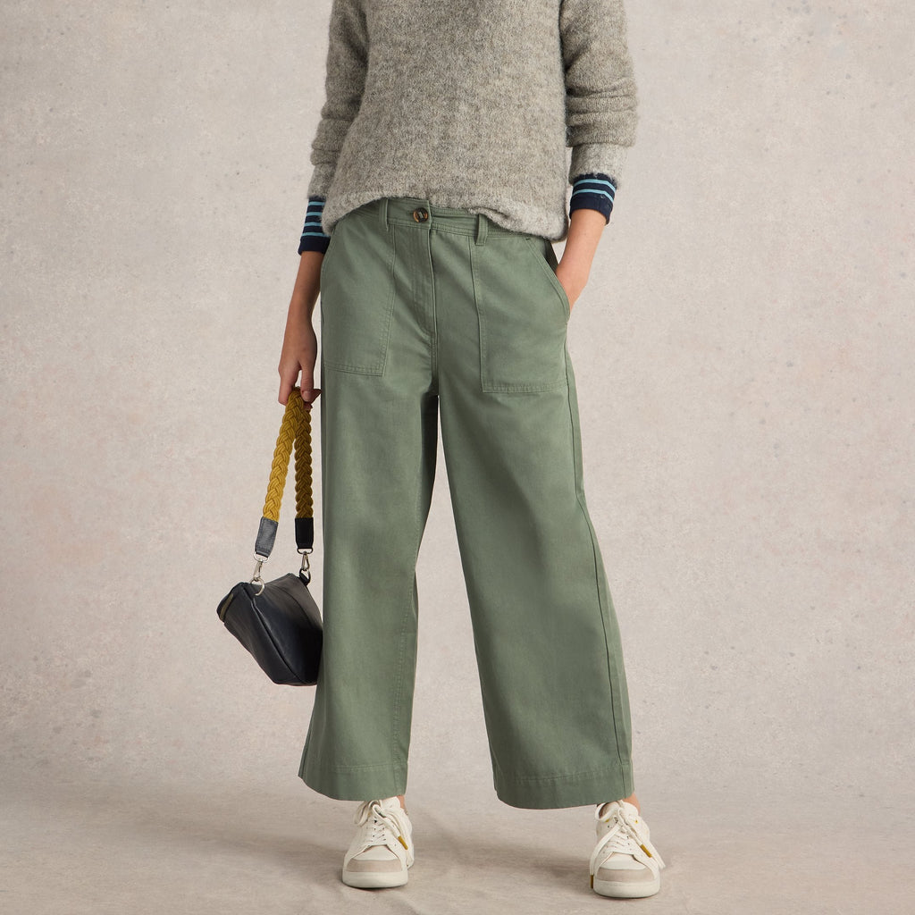 Sage green wide-leg utility pants with front pockets, worn with off-white sneakers.