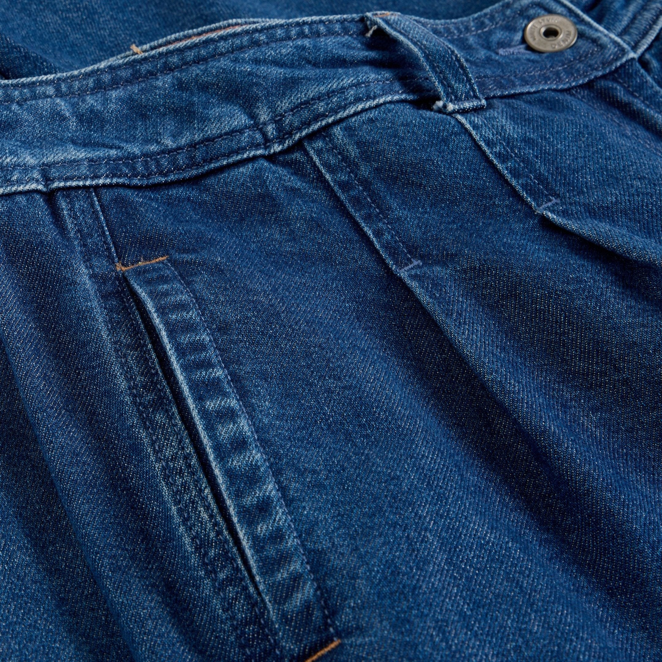 Close-up of dark wash denim jeans, showing texture, stitching, and a button.