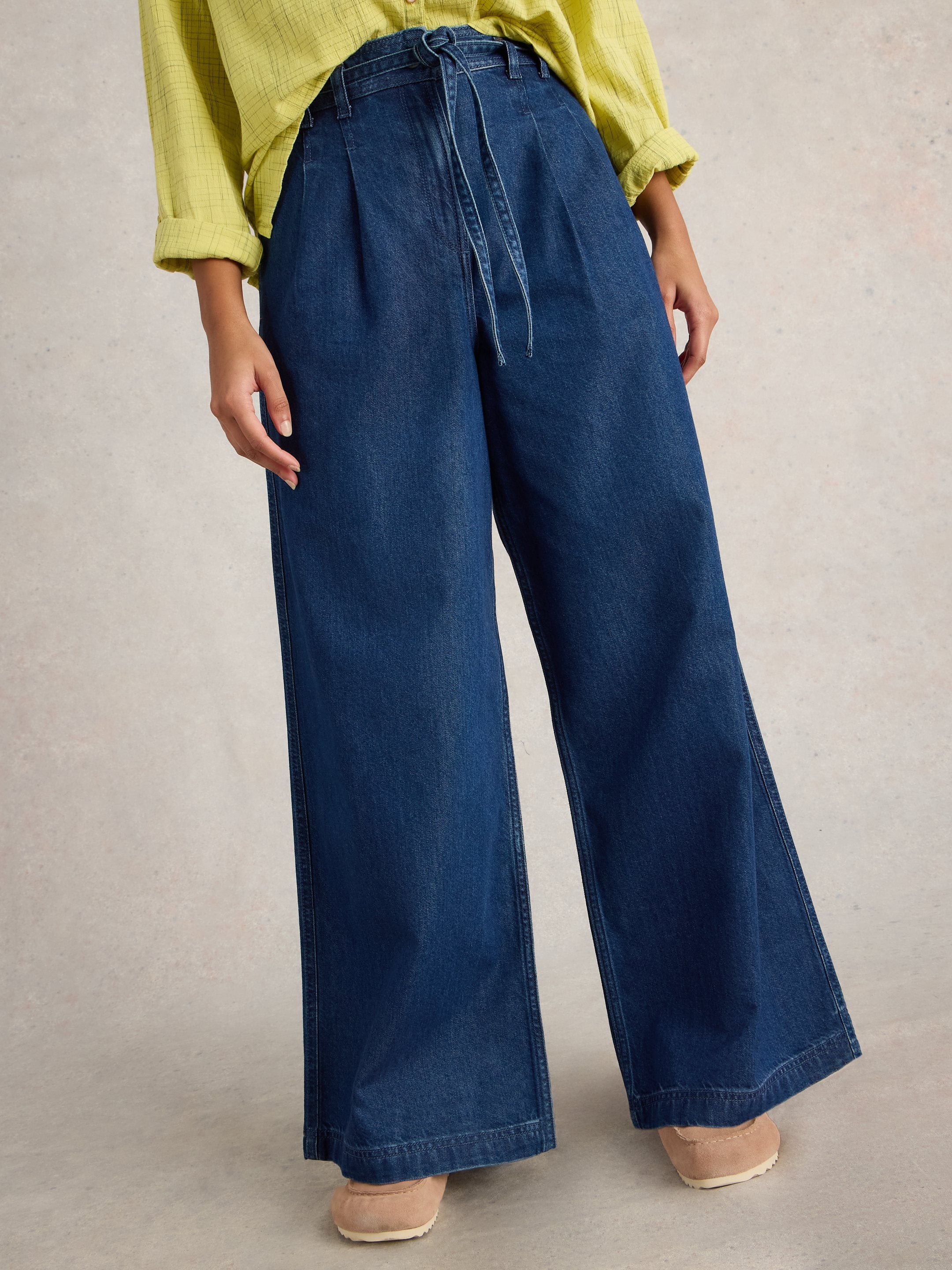 Dark wash denim wide-leg pants with a drawstring waist. Pleated front and a cuffed hem.