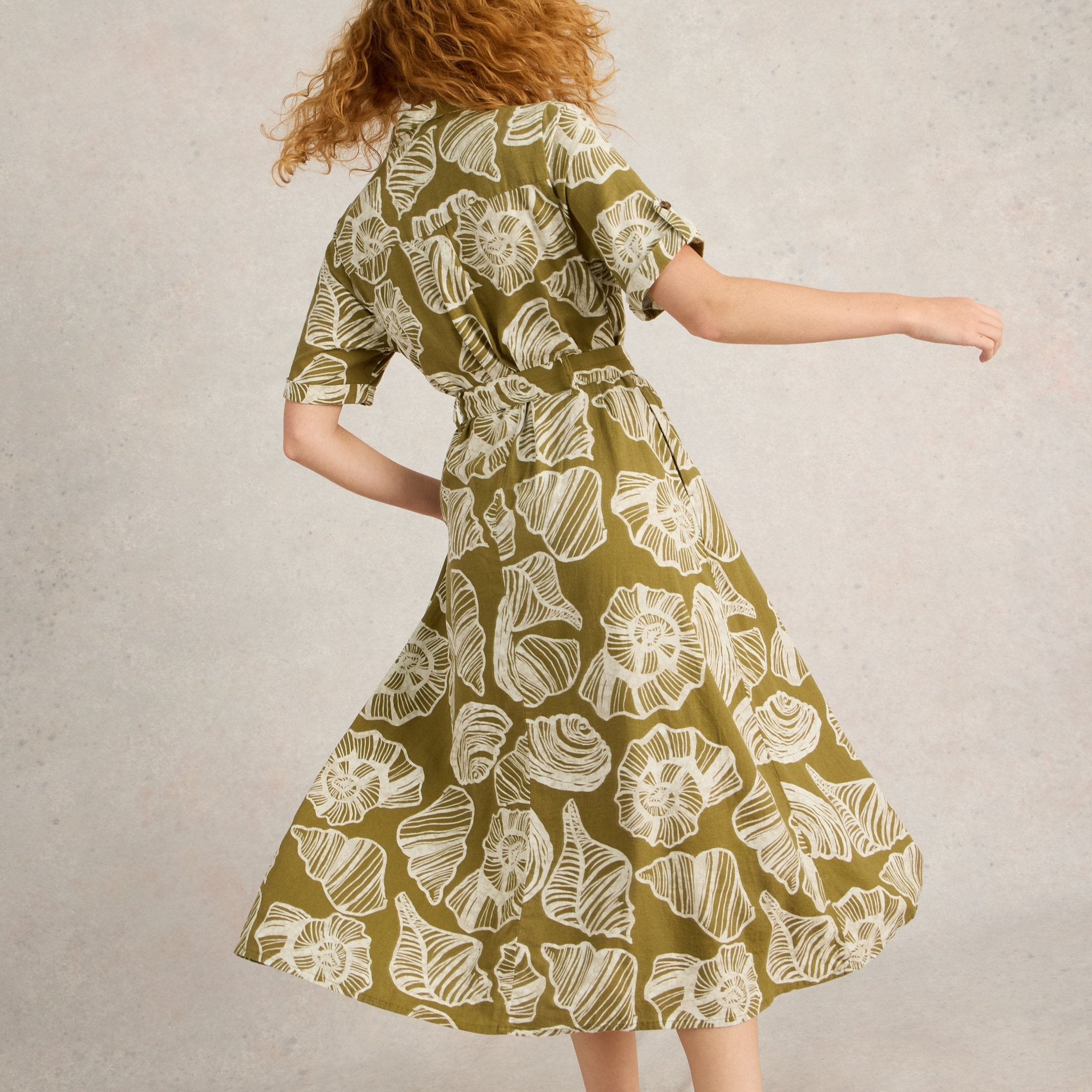 Olive green midi dress with a belted waist and a seashell print. Short sleeves and an A-line silhouette.