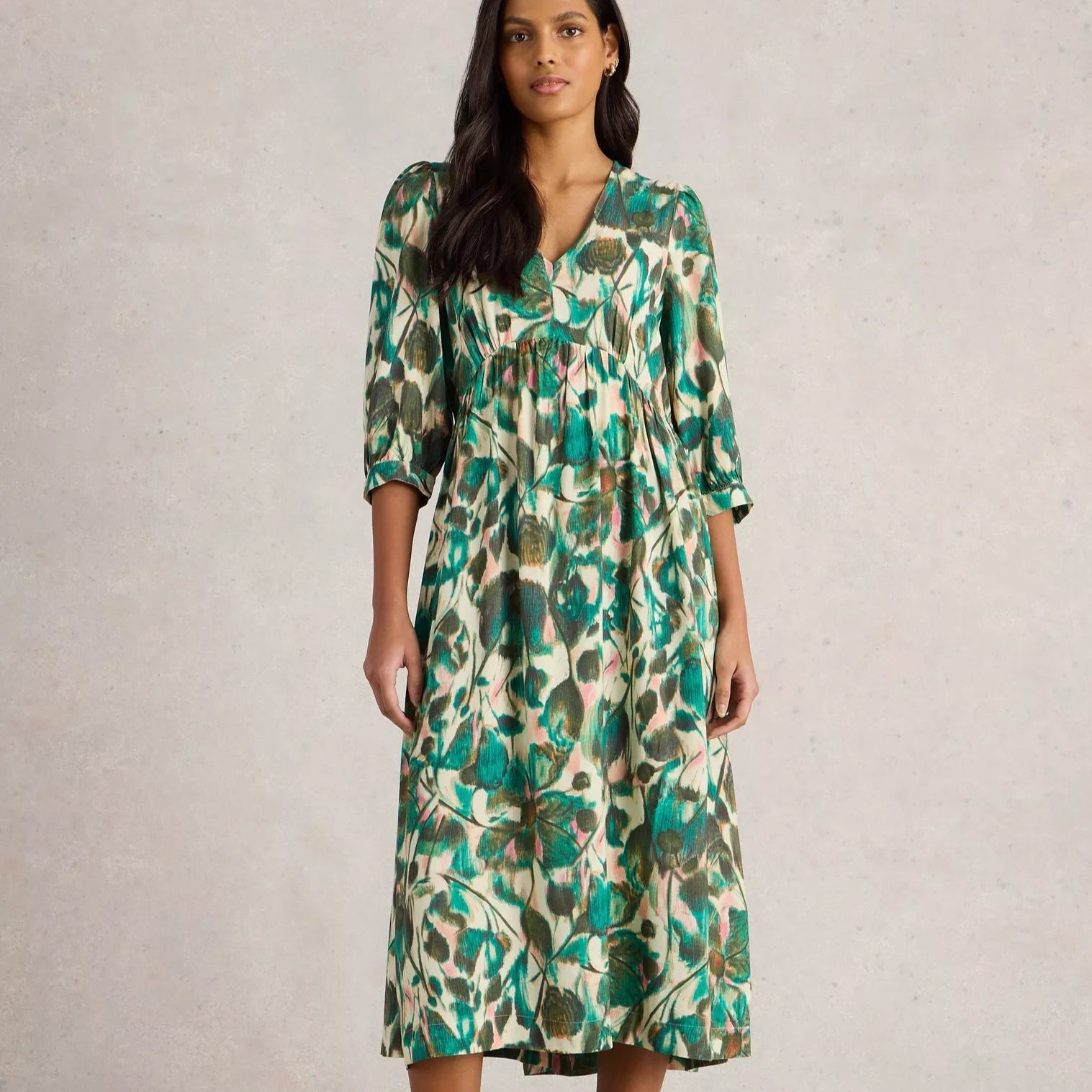Green and cream midi dress with a v-neck and three-quarter sleeves. Features an abstract floral print.