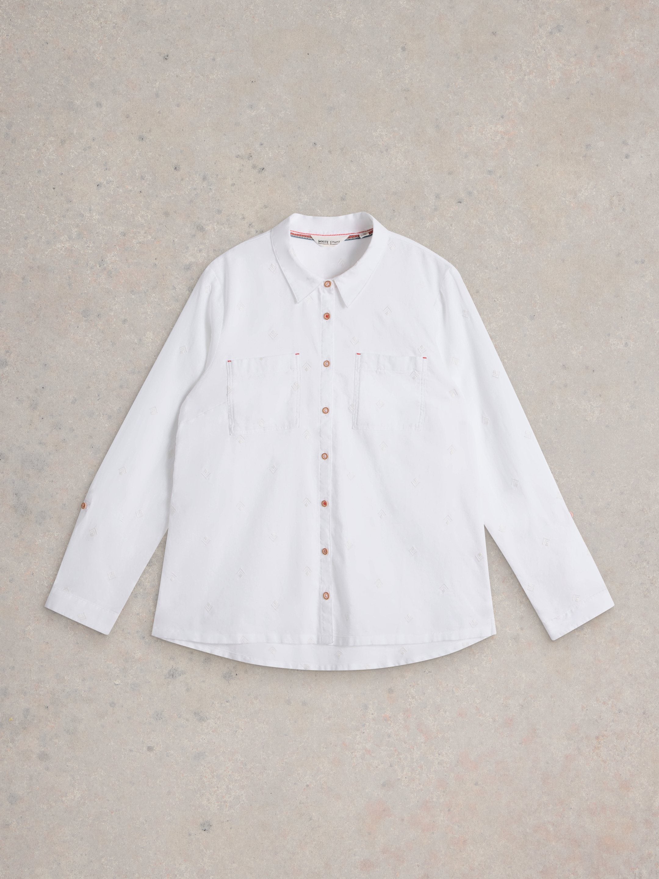 White shirt with brown buttons on a beige background