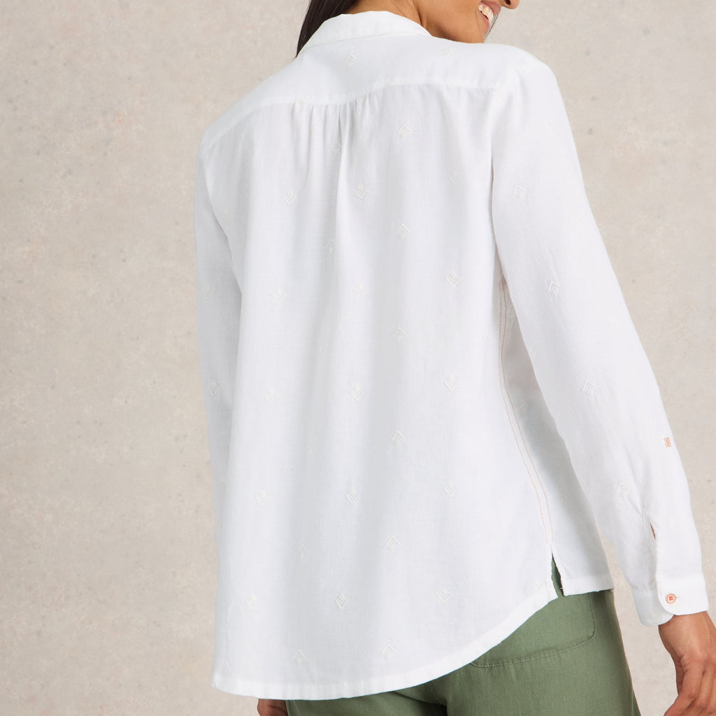 Woman wearing a white blouse with long sleeves against a beige background
