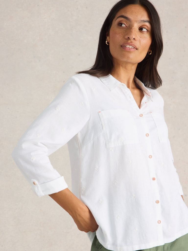 Woman wearing a white button-up shirt against a beige background