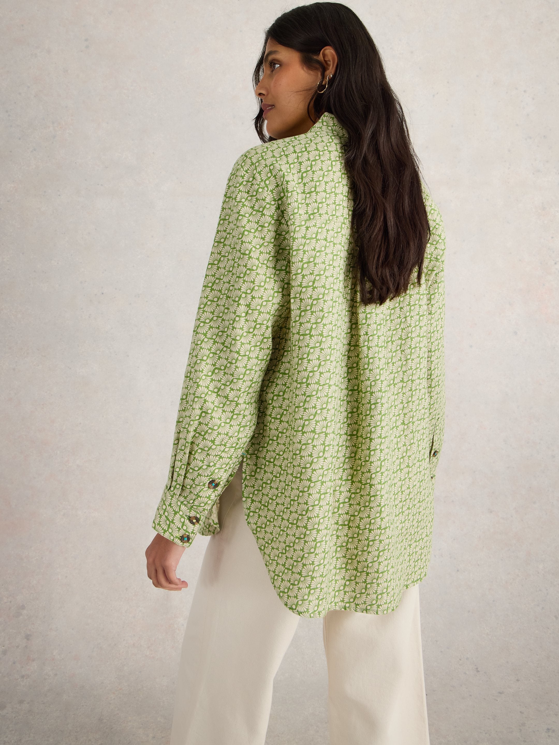Oversized sage green shirt with a repeating off-white floral pattern. Features long sleeves and button cuffs.