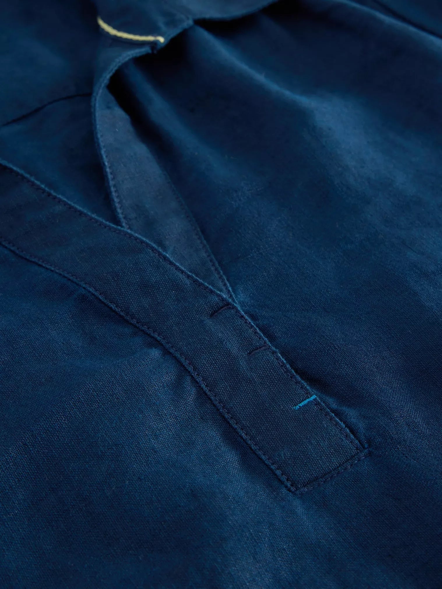 Close-up of dark blue linen fabric with a V-neck and subtle stitching detail.