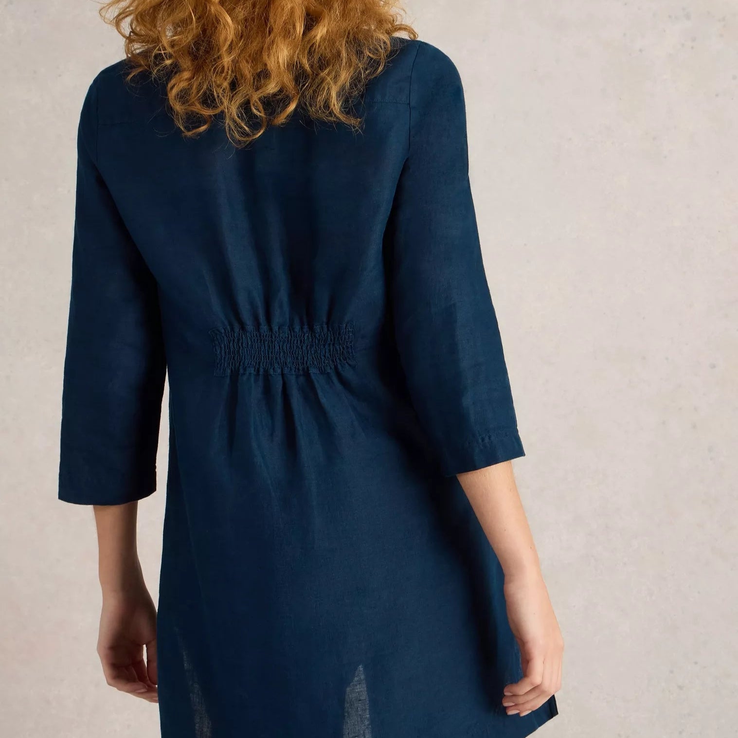 Dark blue linen shirt dress with three-quarter sleeves and smocked back detail.