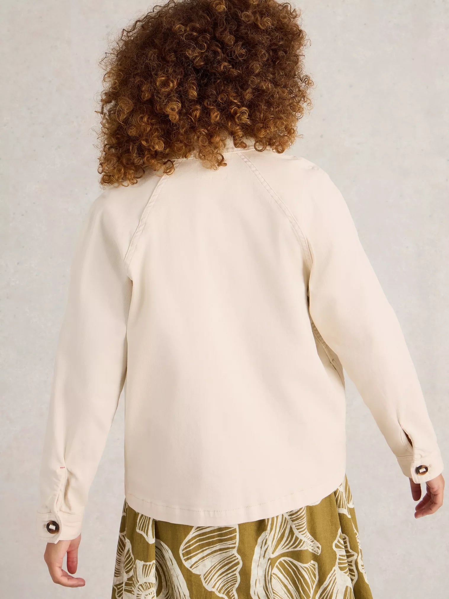 Person wearing a cream blouse with floral skirt on a plain background