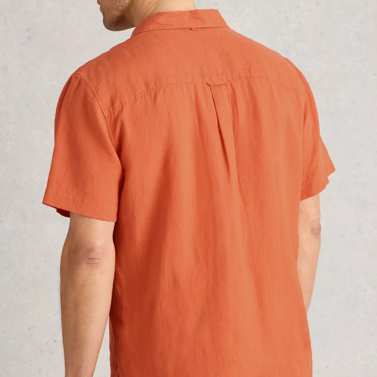 Burnt orange linen short-sleeve button-down shirt, viewed from the back.