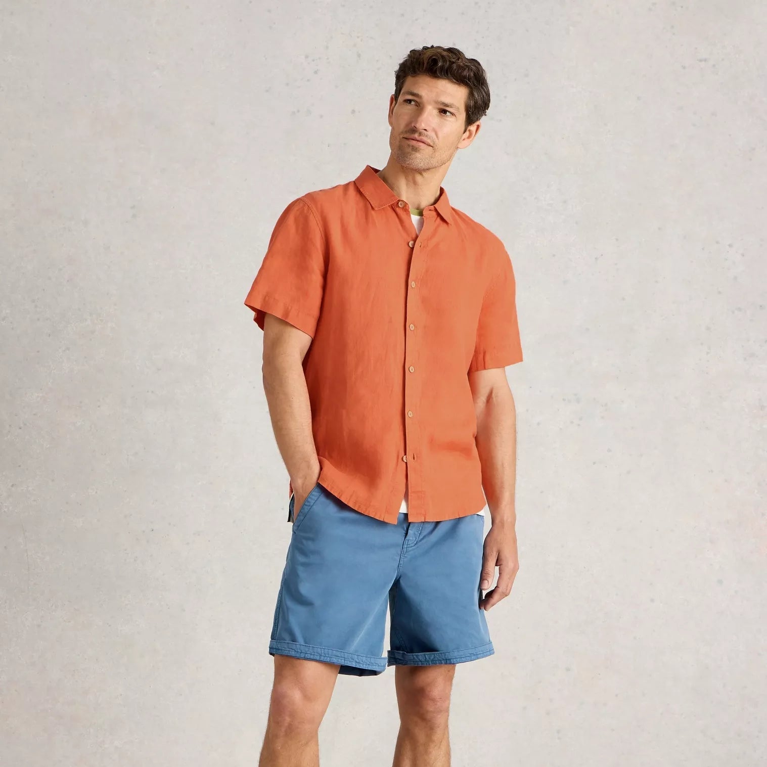 Men's short-sleeved orange linen shirt and blue shorts.