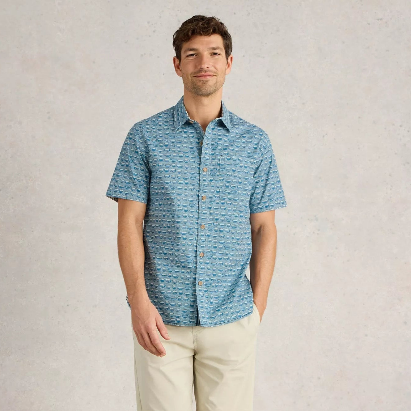 Men's short-sleeve button-down shirt in blue with a repeating pattern of small, stylized cups.