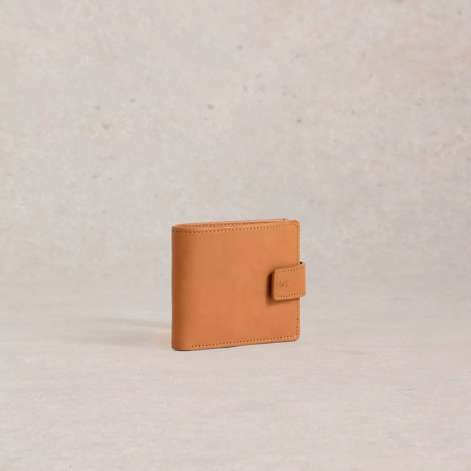 Tan leather wallet on a light beige background
