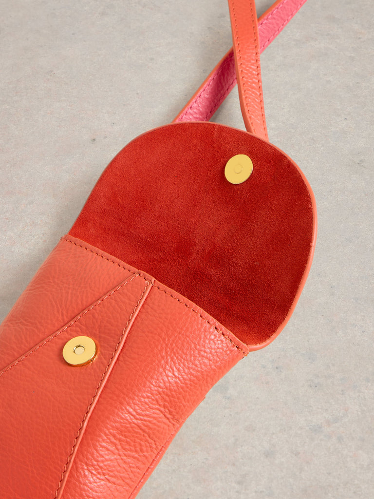 Coral leather crossbody bag open to reveal a red suede interior. Gold-toned magnetic closures are visible.