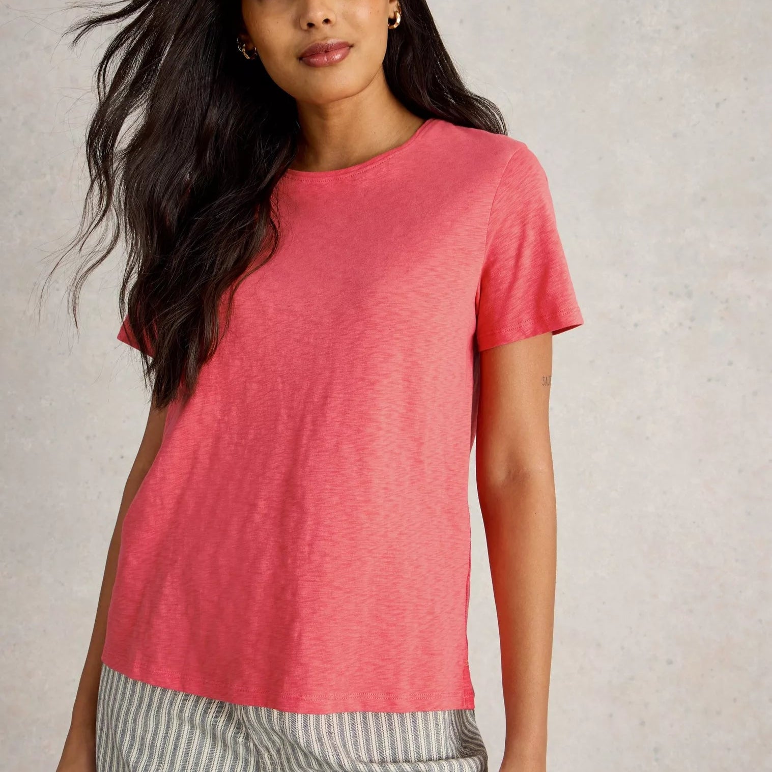 Coral-colored short-sleeve relaxed-fit t-shirt with a round neckline and a slightly textured fabric.