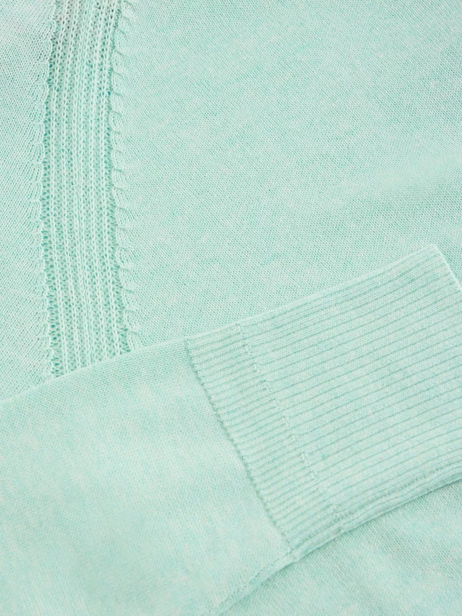 Close-up of pale mint green knit fabric with textured detail at the center.