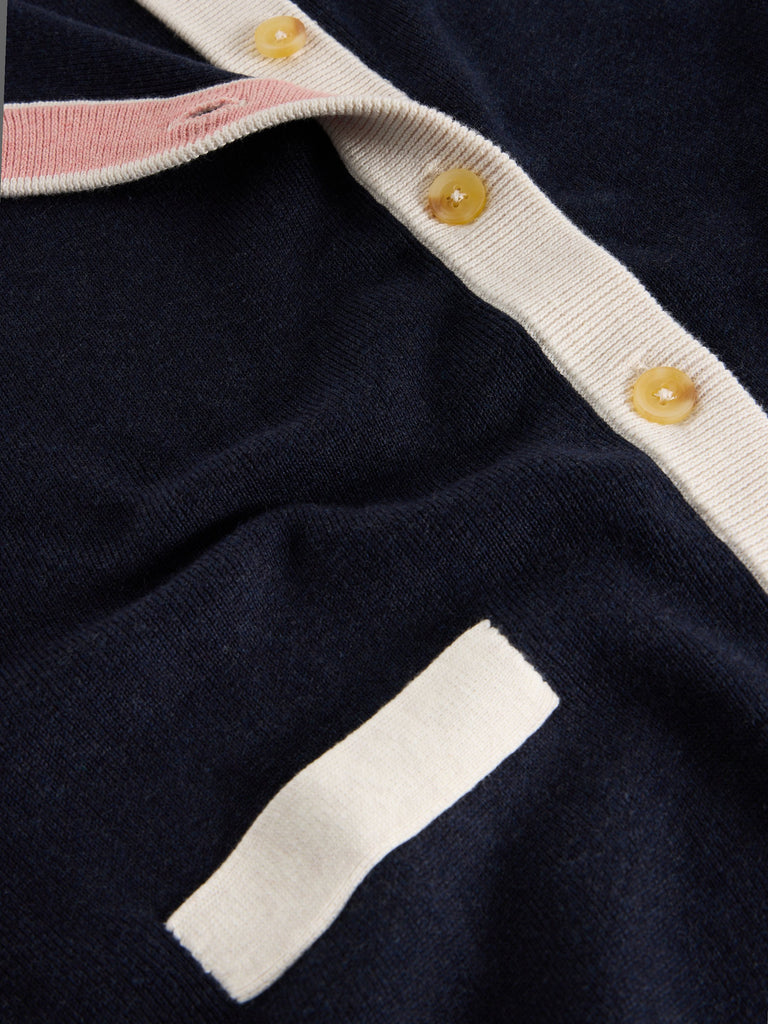 Navy blue knitted cardigan with cream and blush pink trim, featuring button closures.