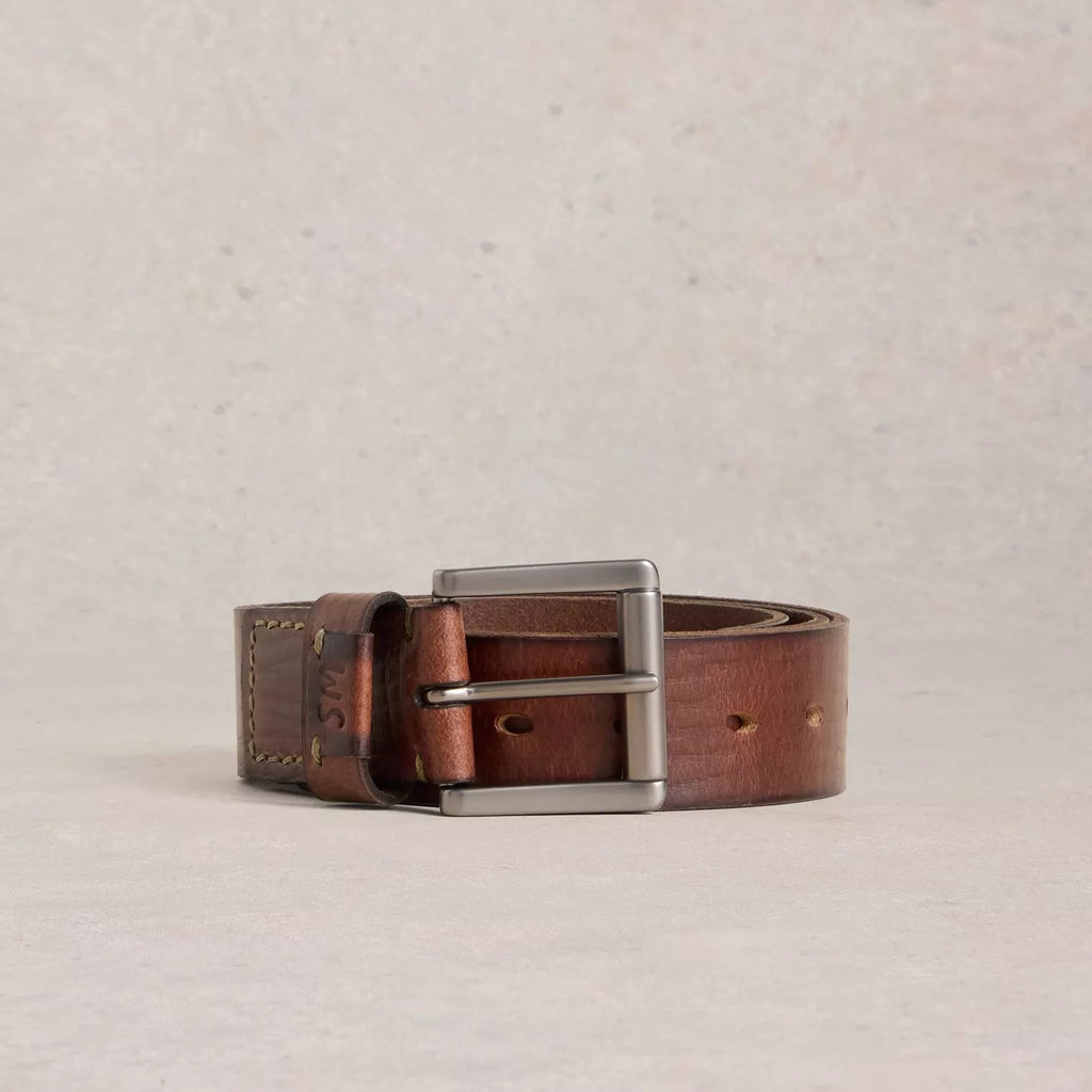 Brown leather belt with silver buckle on a beige background