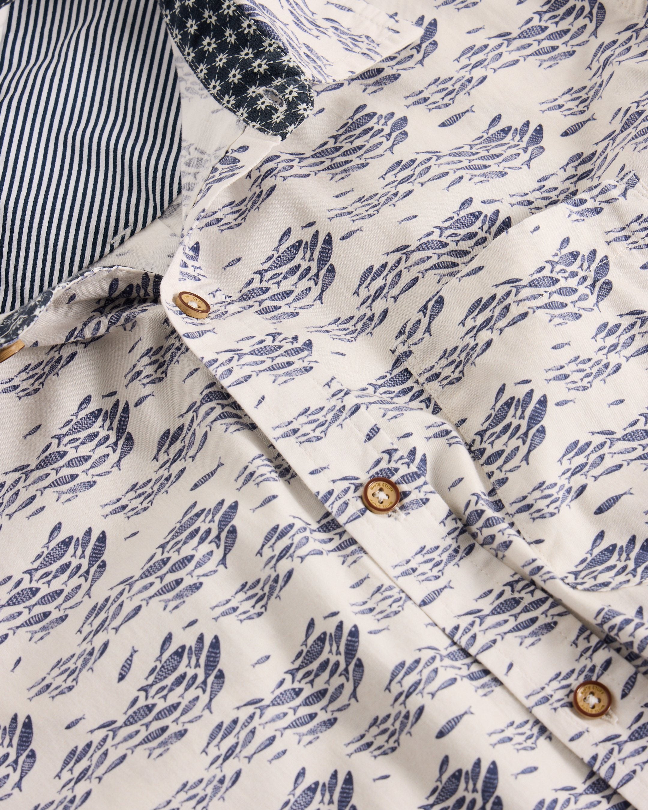 Off-white button-down shirt with a navy fish print. The collar features a contrasting navy and white striped fabric.
