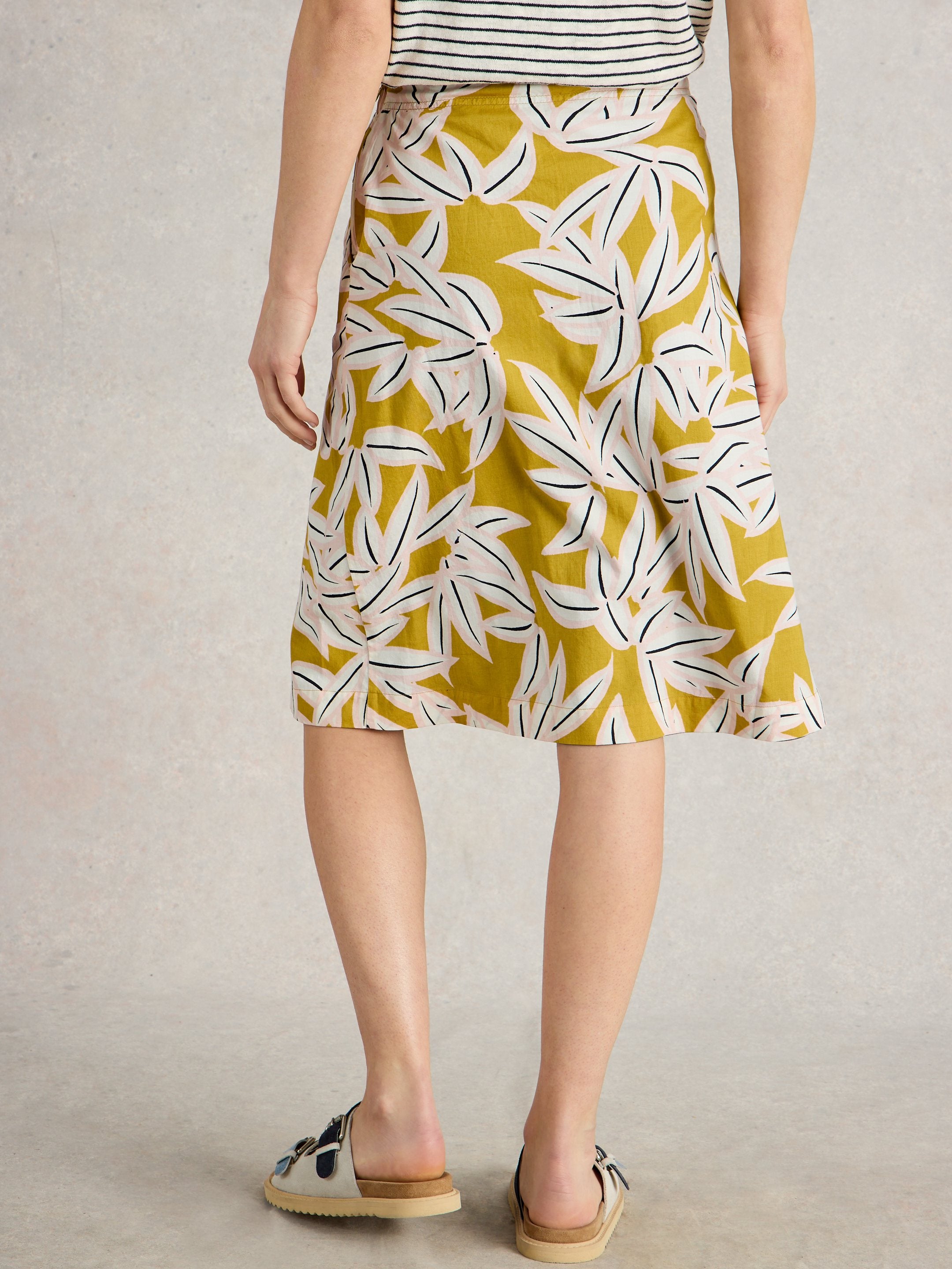 Mustard yellow midi skirt with a pink and white stylized leaf print.