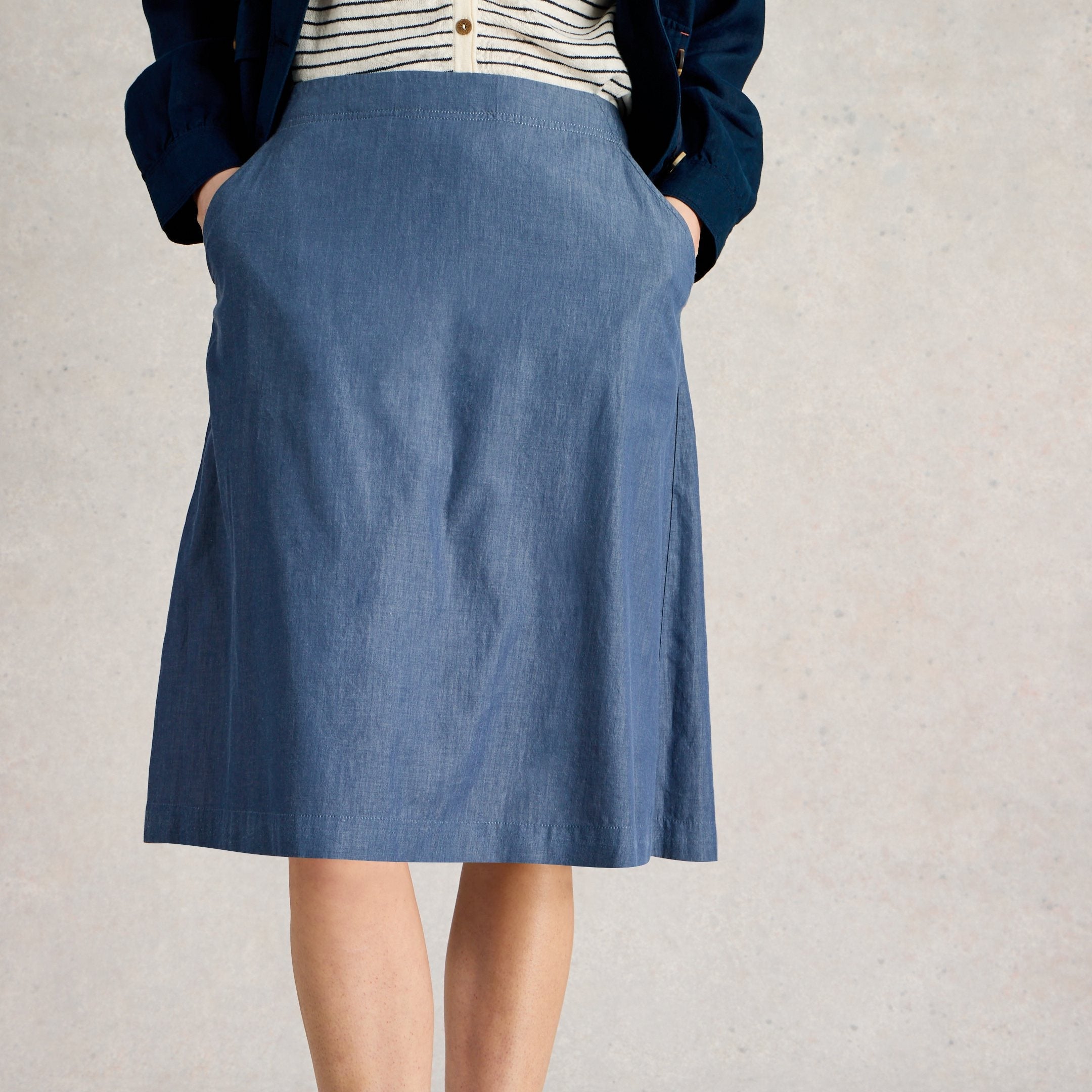 A-line denim skirt with pockets, mid-length, blue wash.