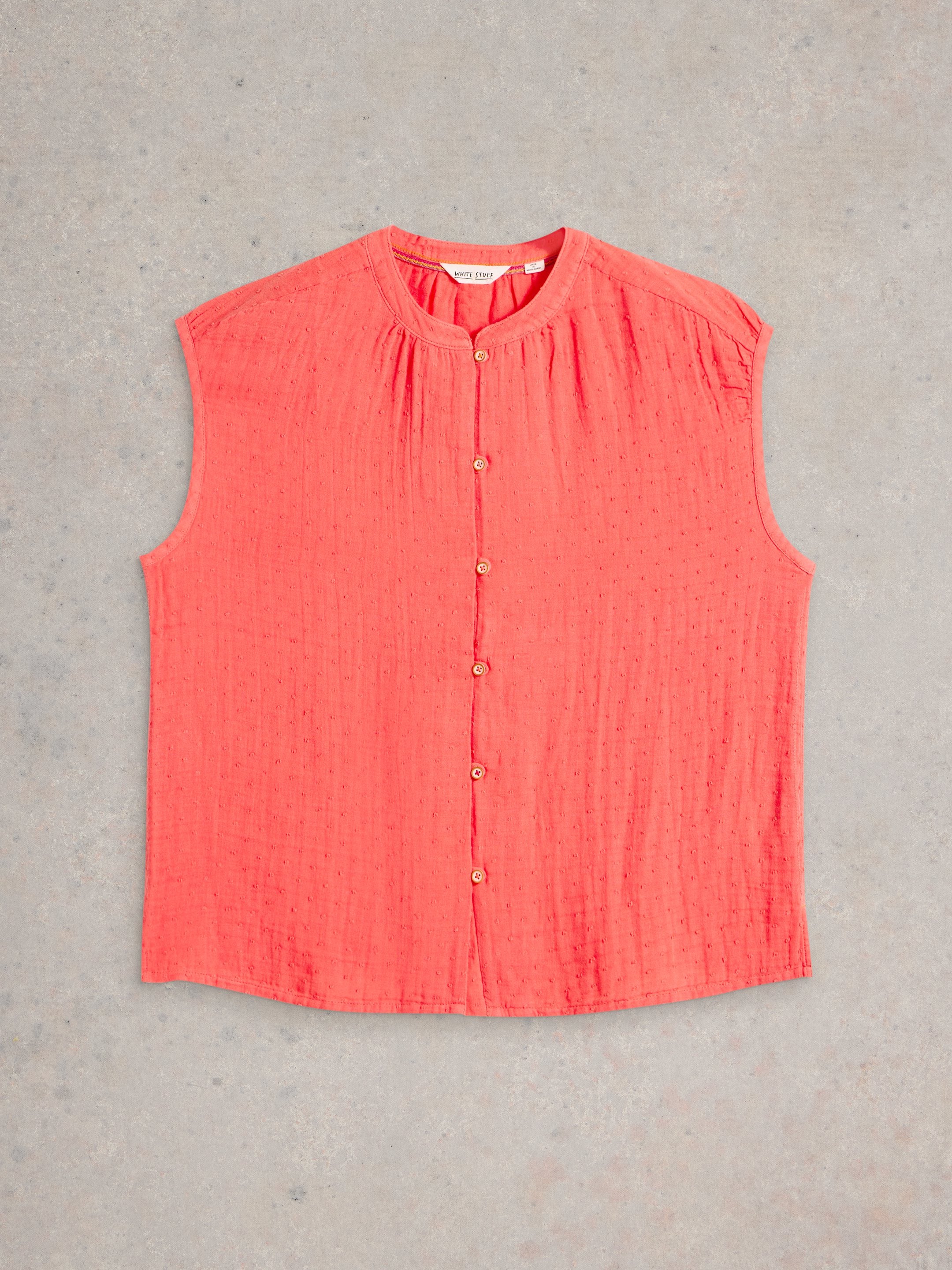 Coral sleeveless button-down top with textured fabric.