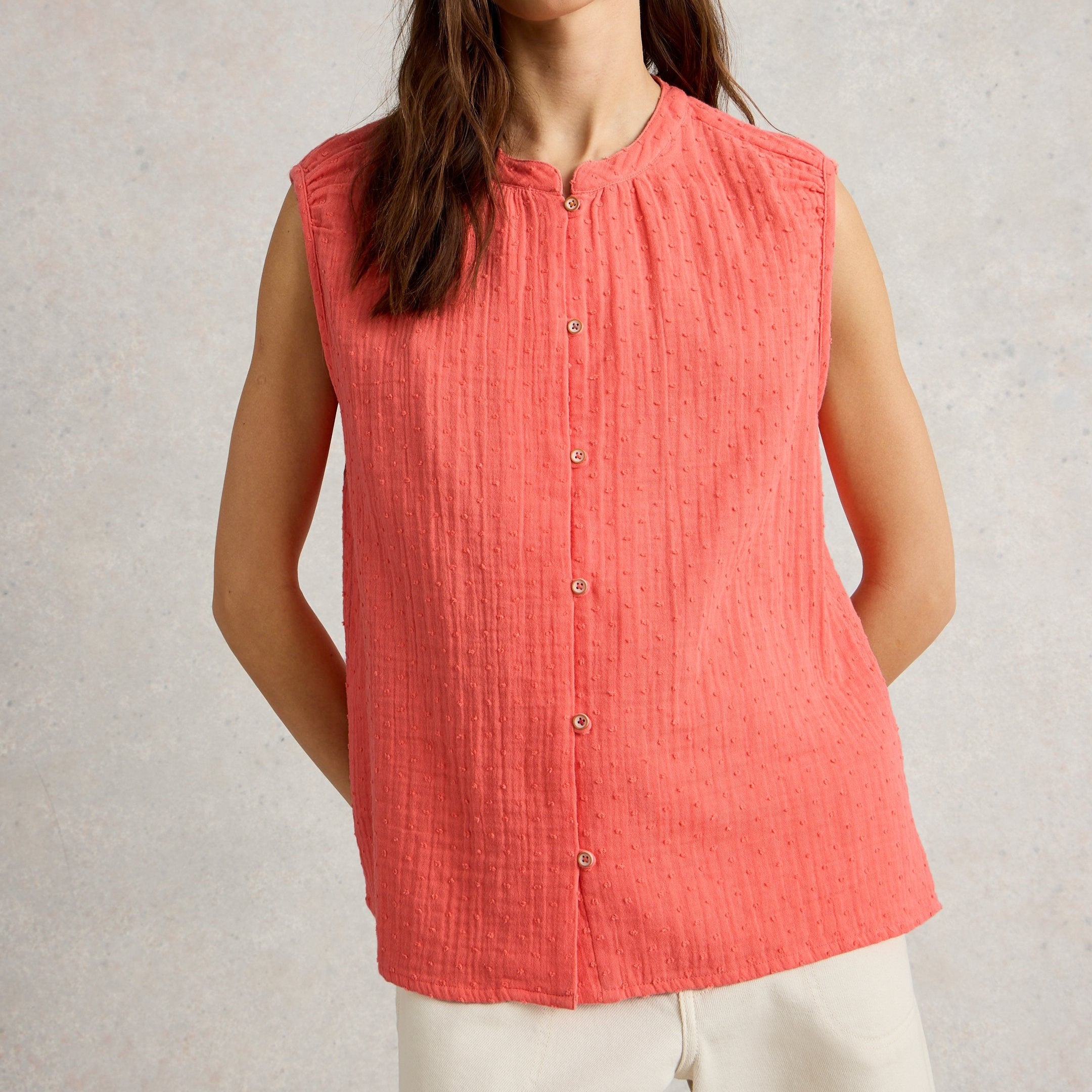 Coral sleeveless button-down top with textured fabric.