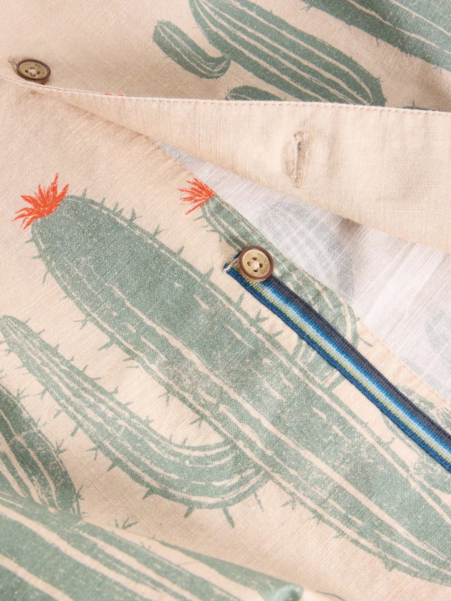 Beige linen shirt with a repeating cactus print in muted green.