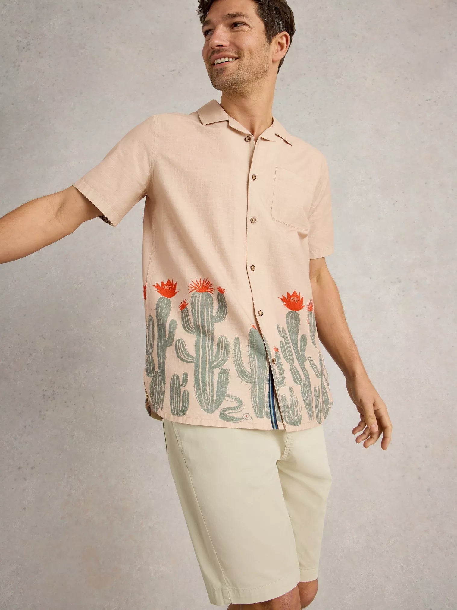 Men's short-sleeved, light beige linen shirt featuring a cactus print along the bottom hem.