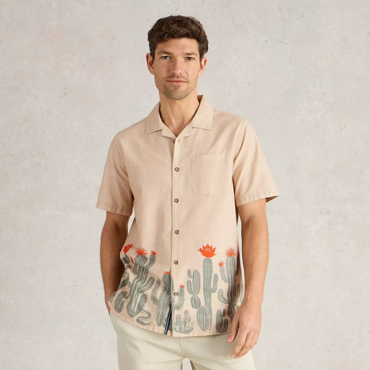 Beige short-sleeved button-down shirt with a cactus print at the bottom hem.