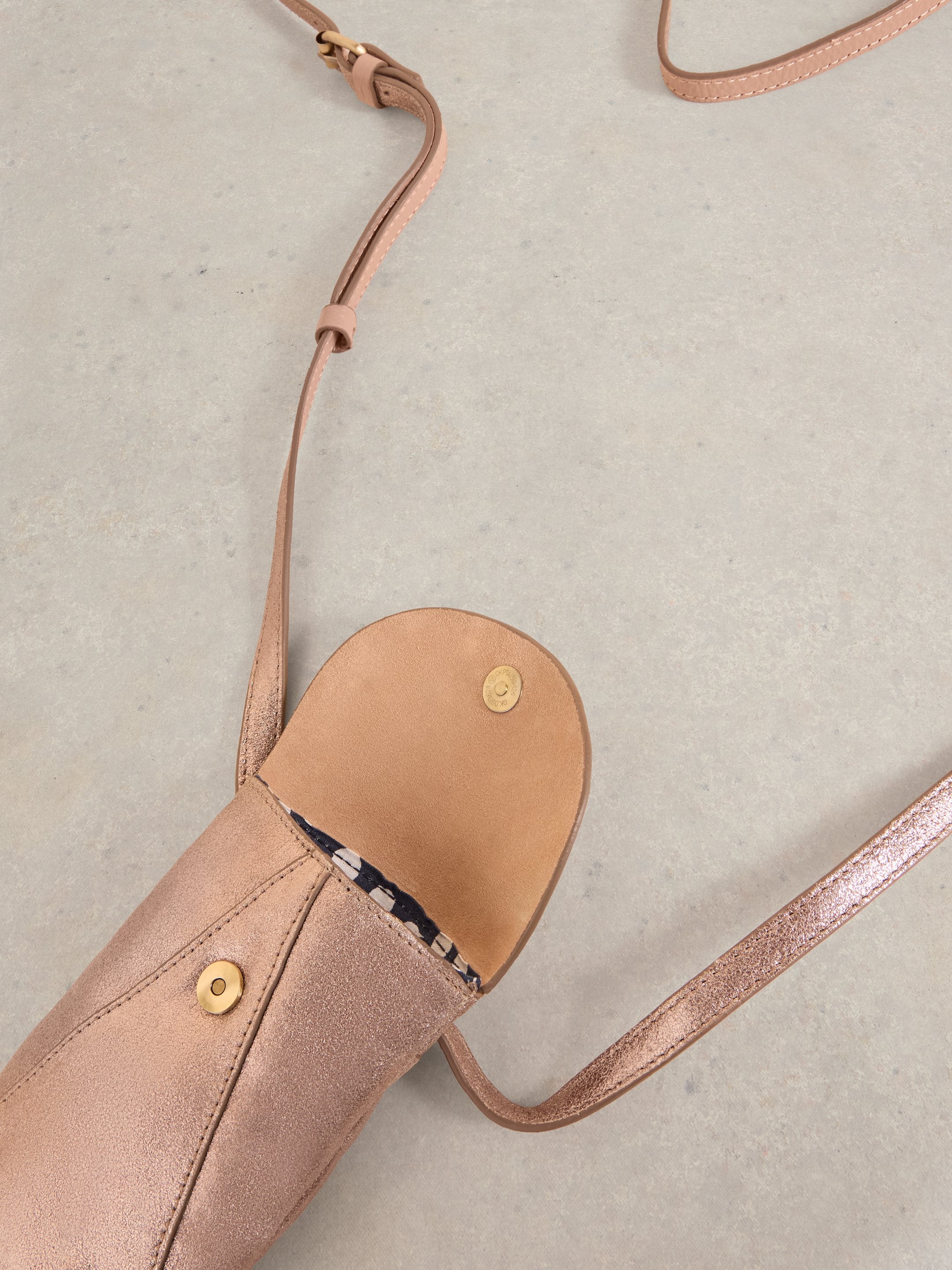 Rose gold crossbody bag with a suede-like texture and a light brown leather interior.
