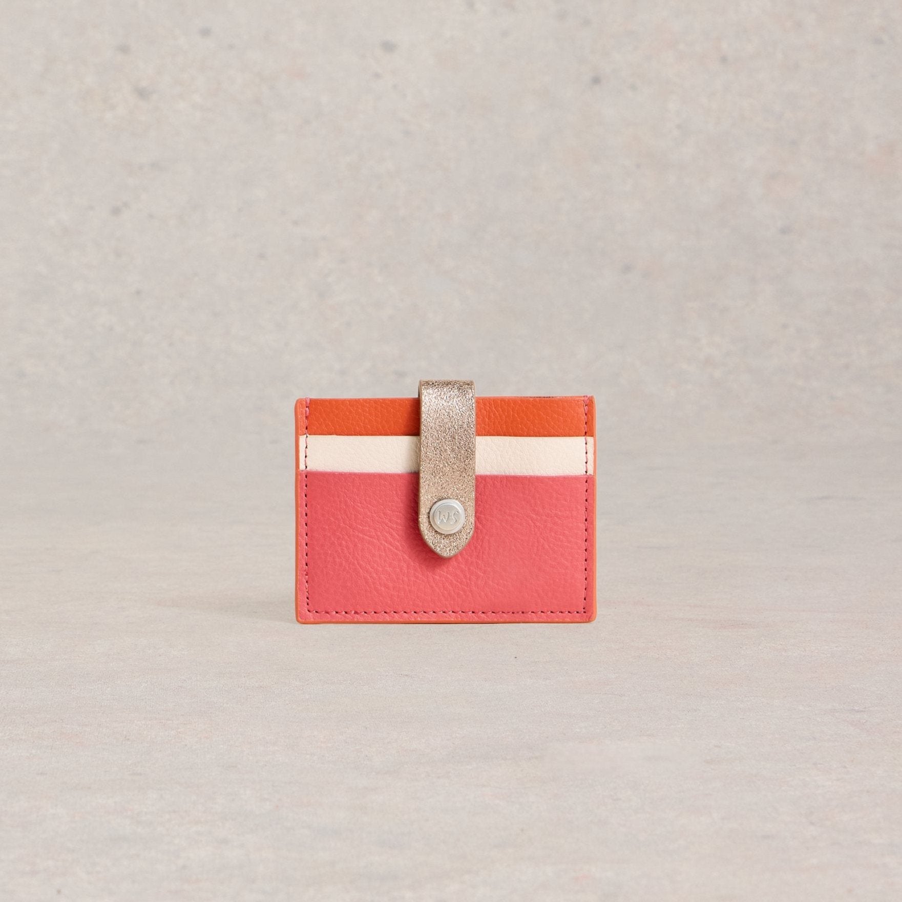 Coral pink leather cardholder with orange and cream stripes and a metallic gold closure.