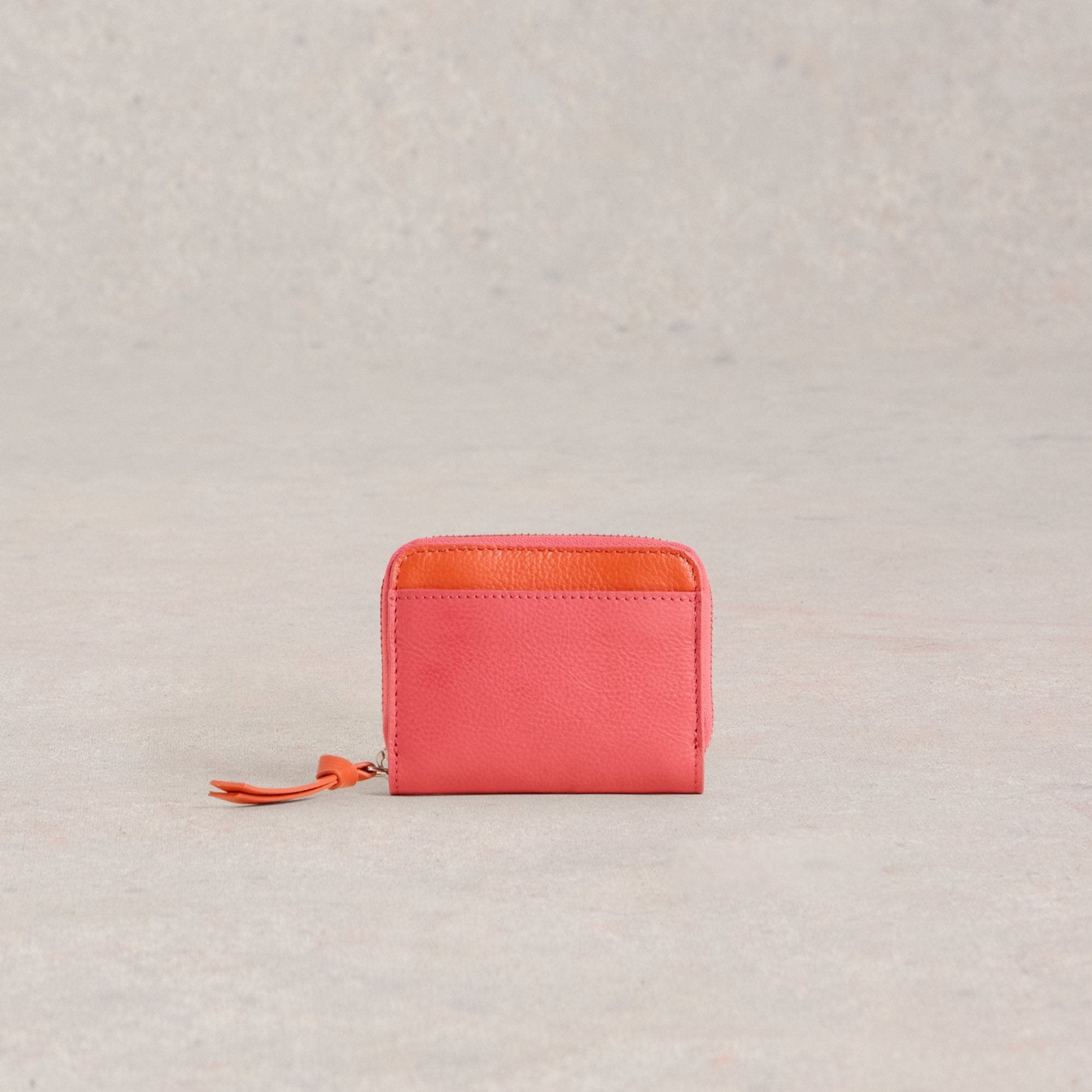 Coral leather zip-around wallet with an orange interior.