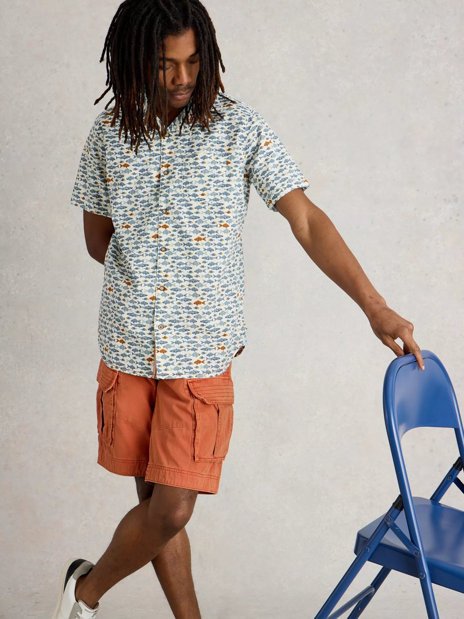Short-sleeved button-down shirt with a repeating fish pattern on a light background.