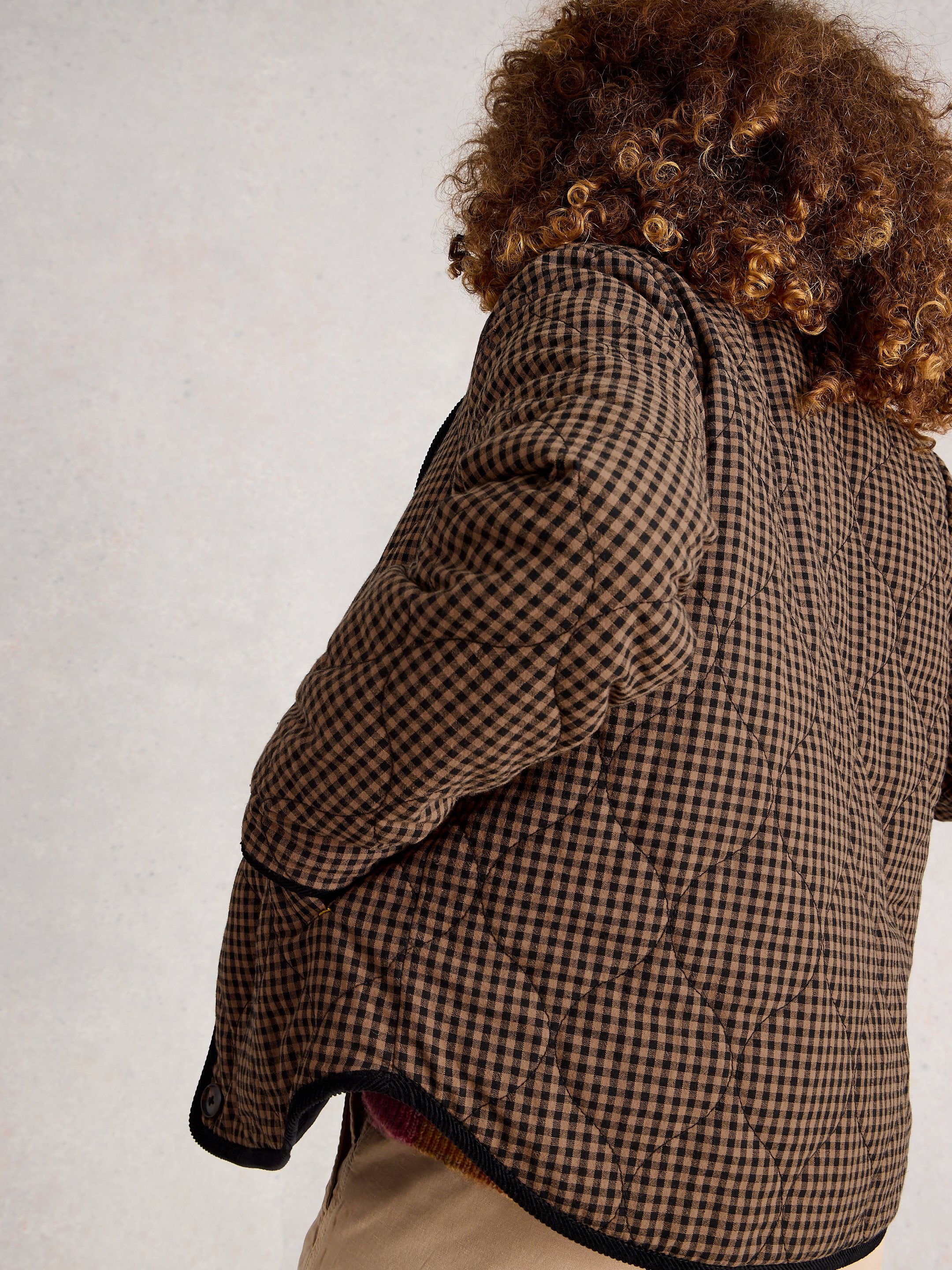 Person wearing a plaid jacket with a neutral background