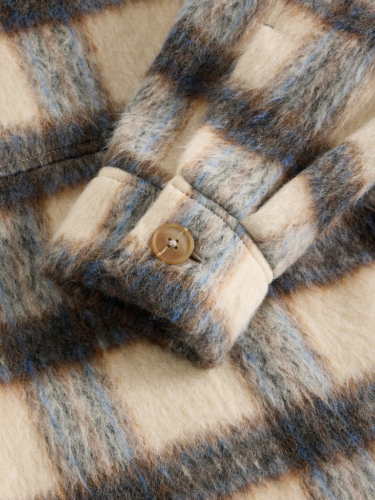Close-up of a plaid fabric with a button, showing texture and pattern details.