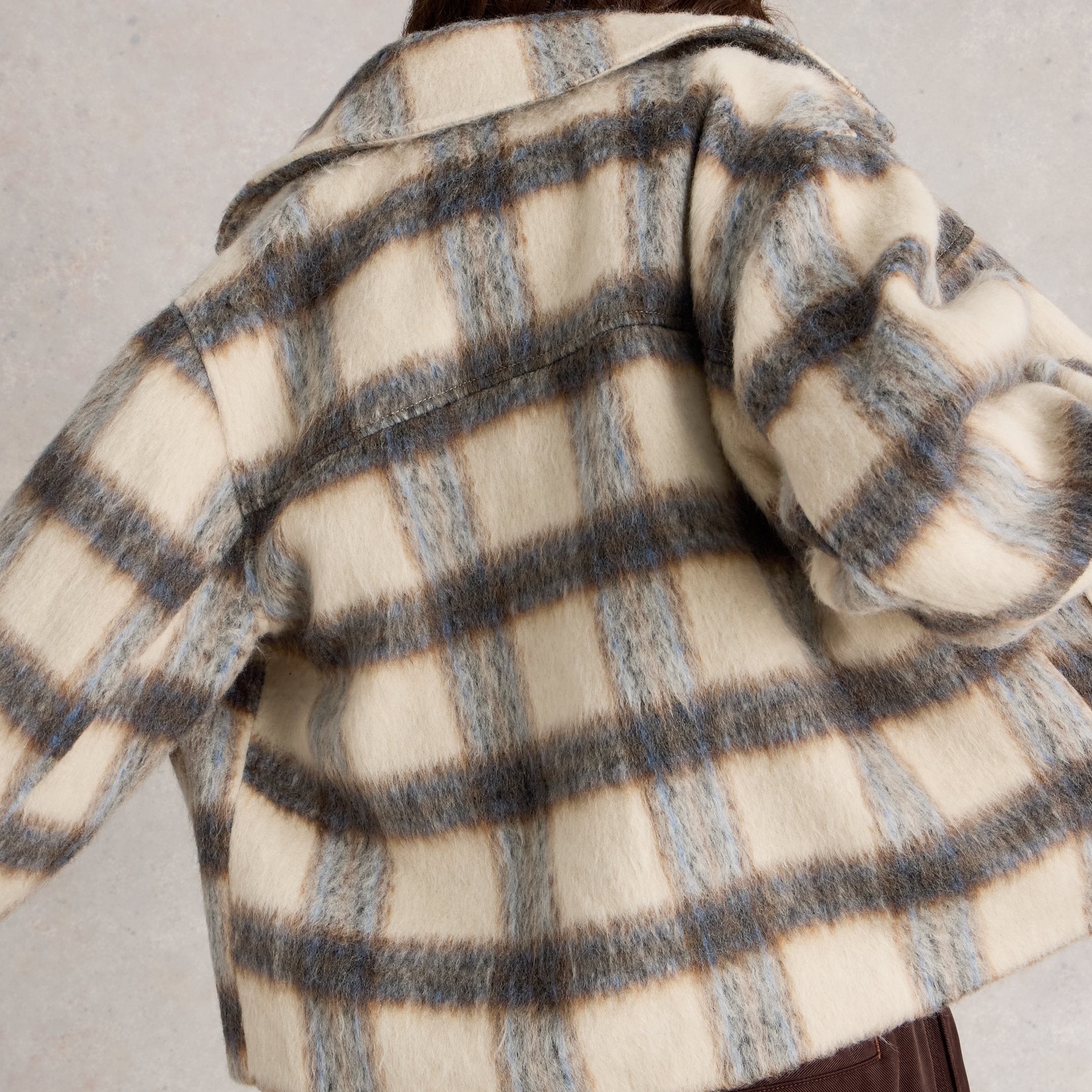 Person wearing a checkered coat with a neutral background
