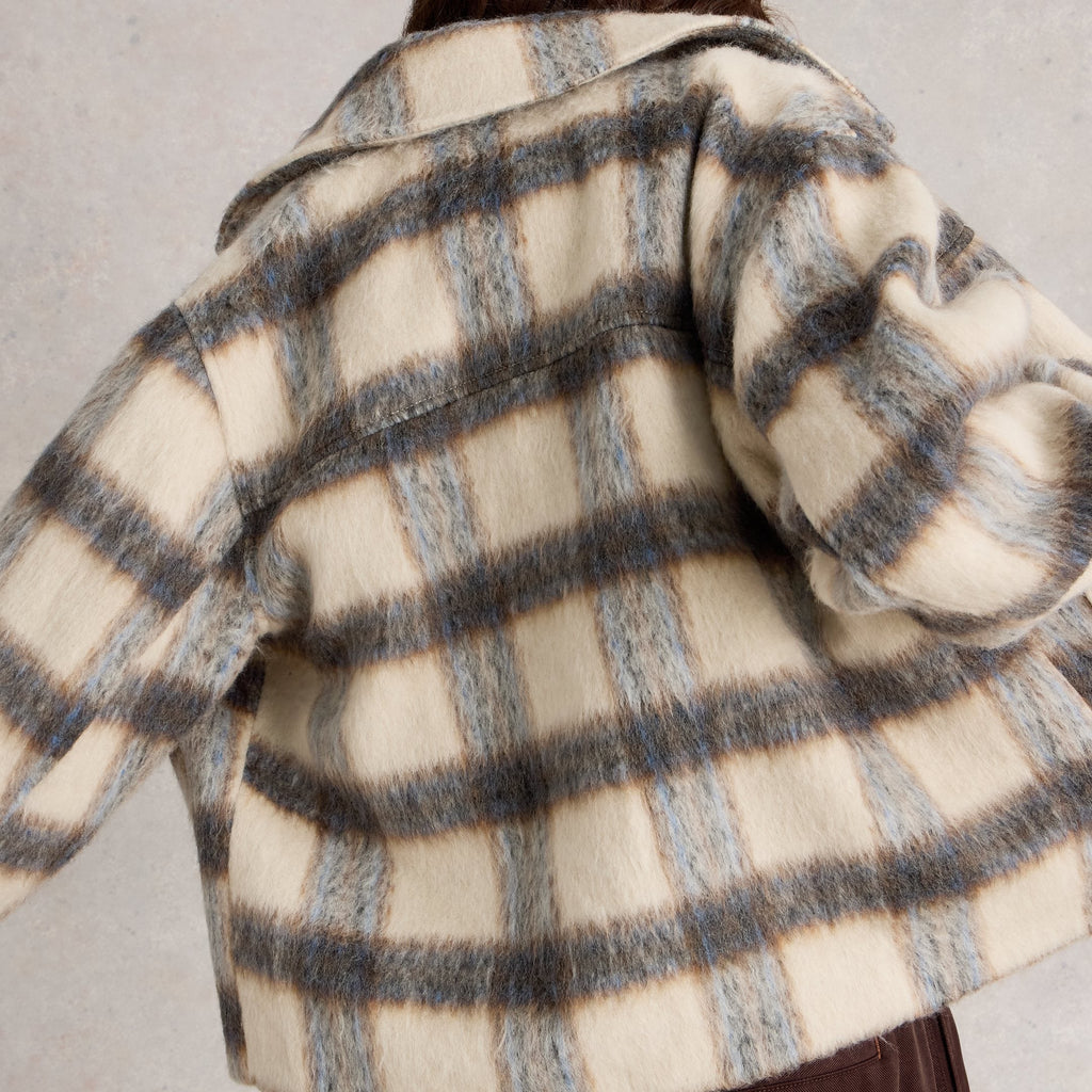 Person wearing a checkered coat with a neutral background
