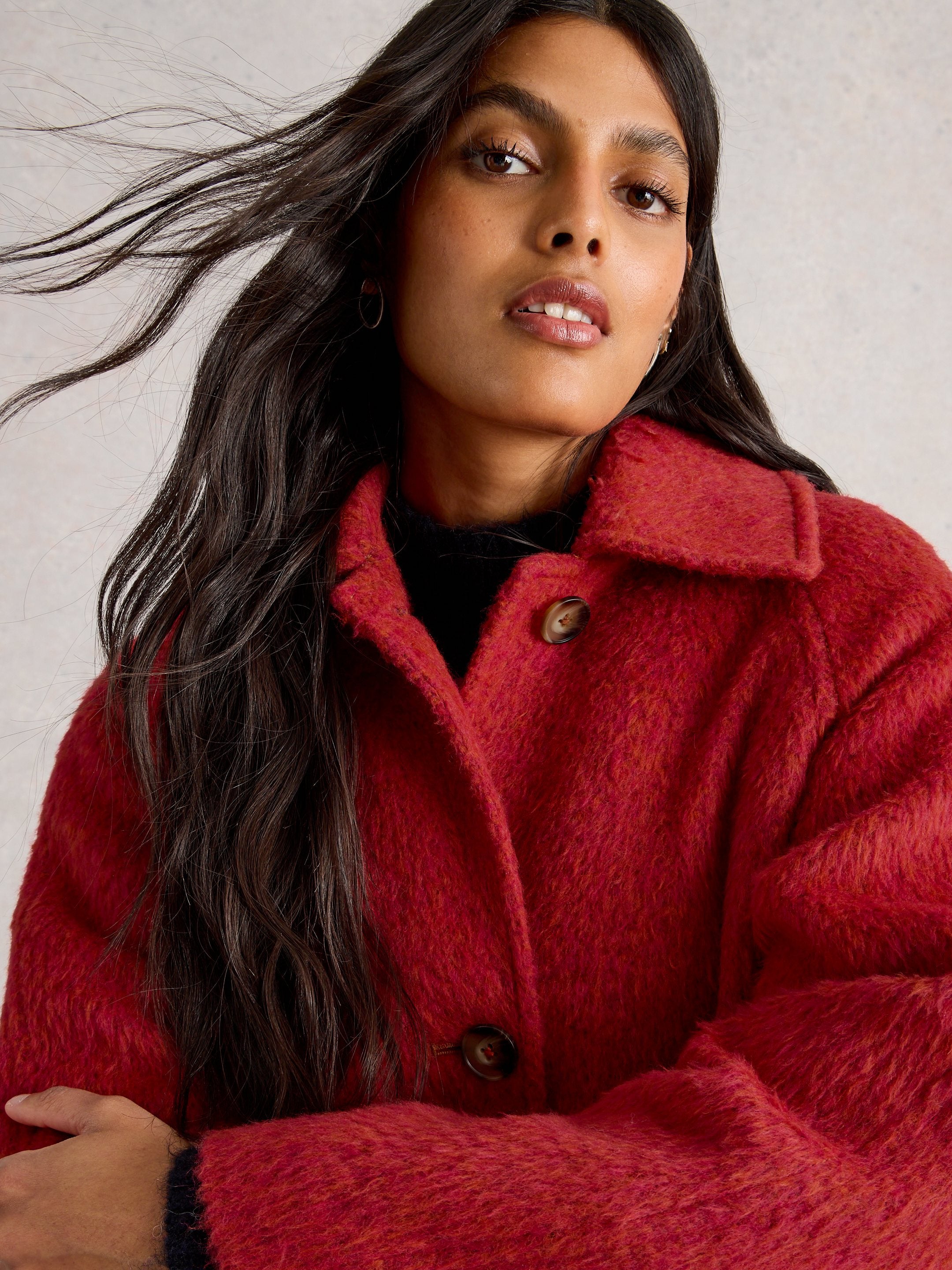 Woman wearing a red coat against a neutral background