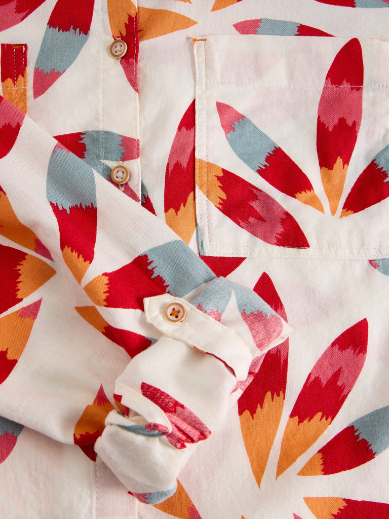 Close-up of a colorful patterned shirt with red, orange, and blue abstract design on a white background.