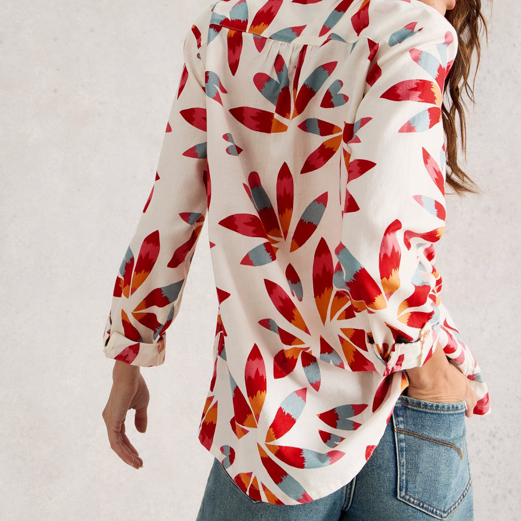 Woman wearing a colorful floral shirt with a plain background