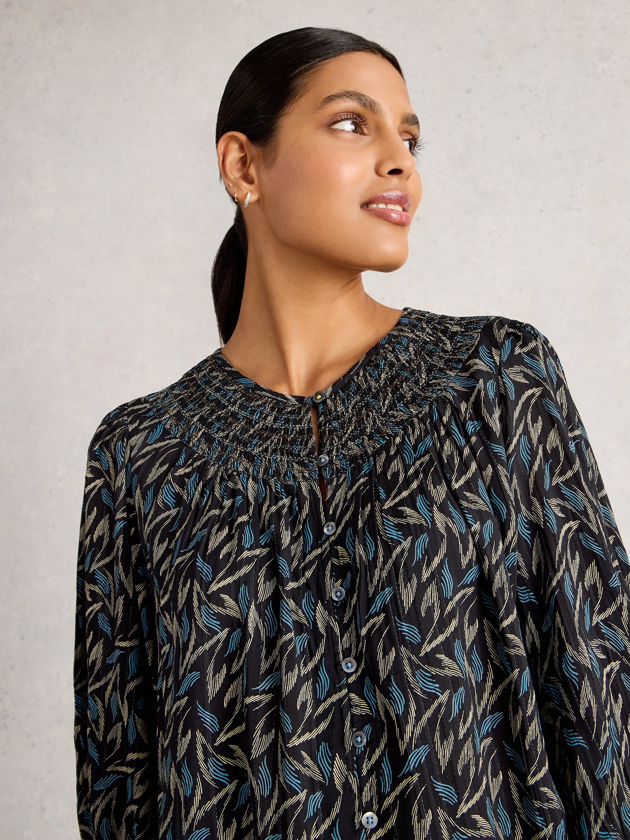 Woman wearing a patterned blouse against a plain background