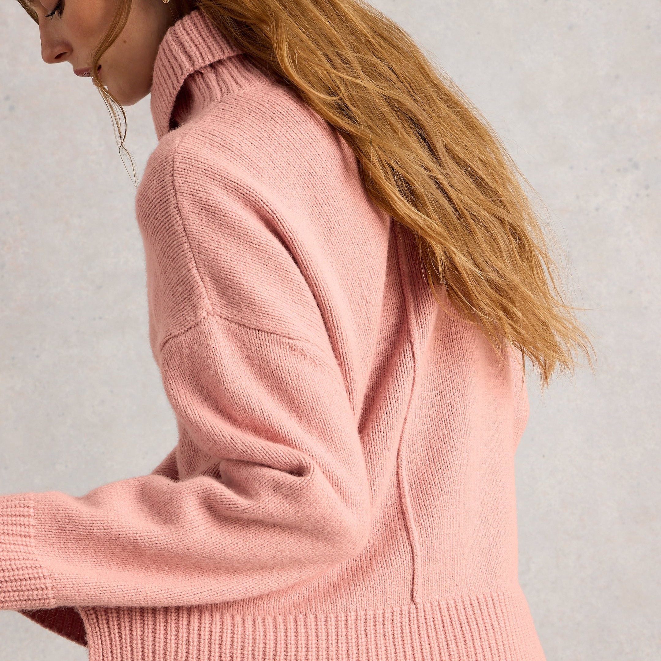 Woman wearing a pink sweater against a plain background