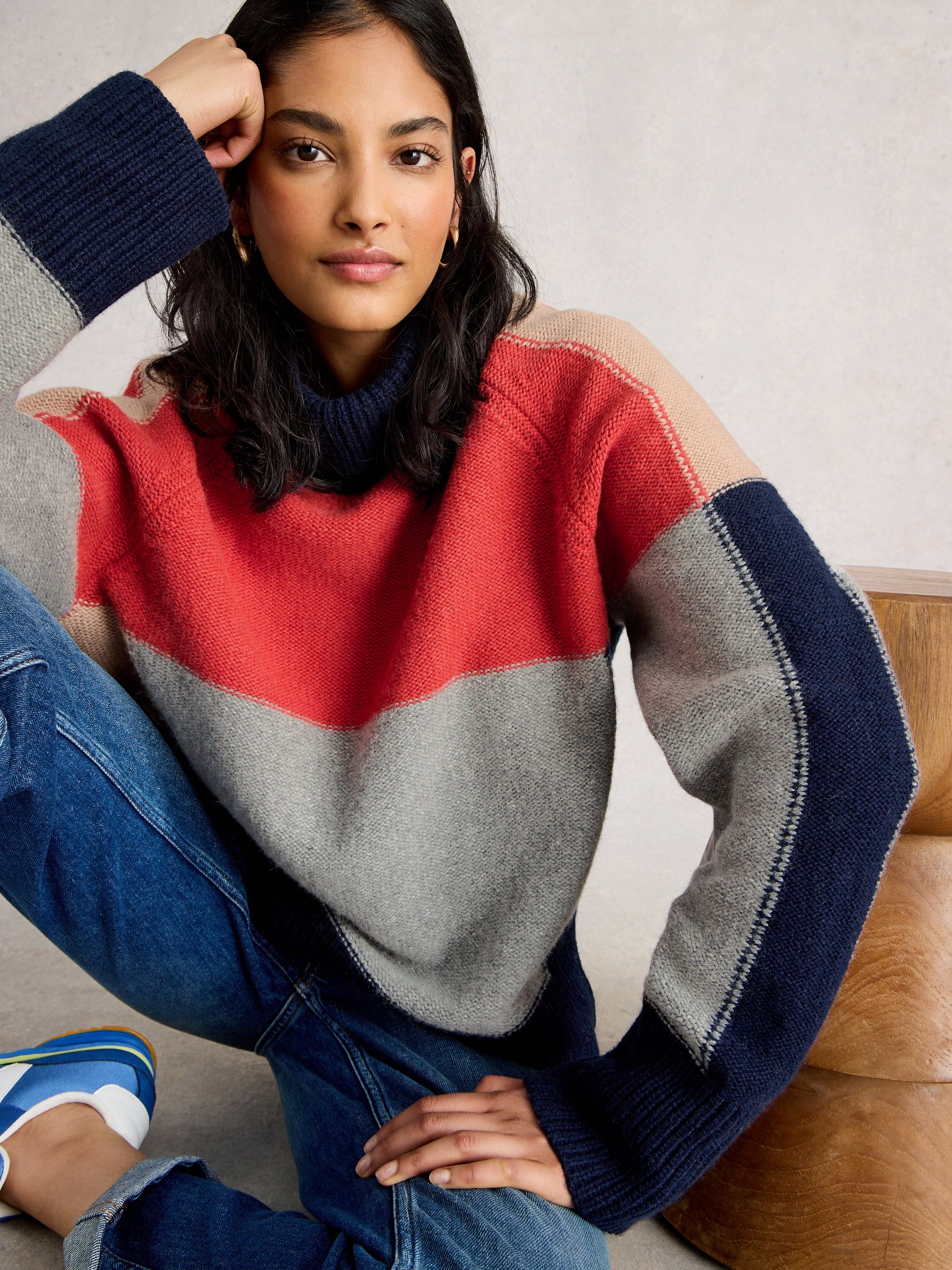 Woman wearing a colorful sweater sitting on a couch.