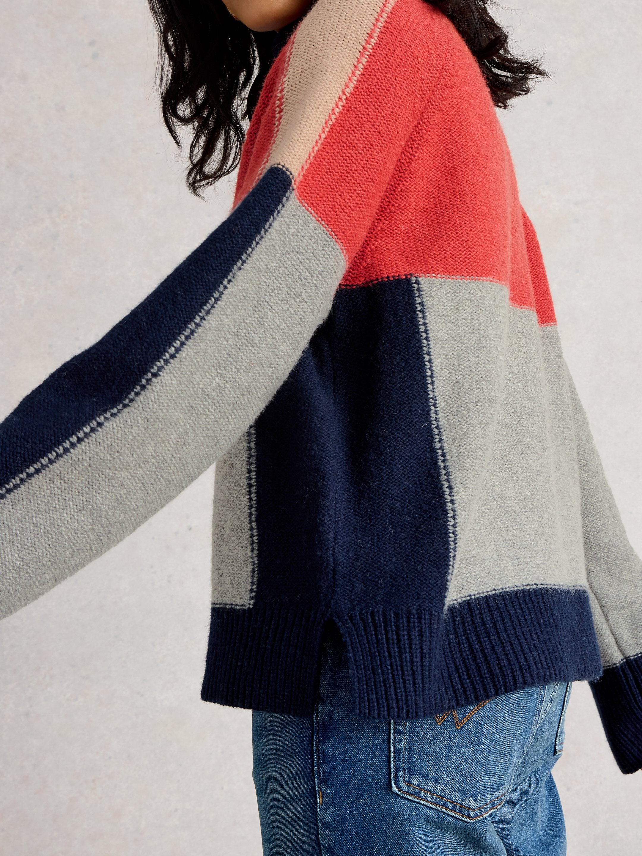 Color-blocked sweater with red, blue, and gray sections worn by a person.