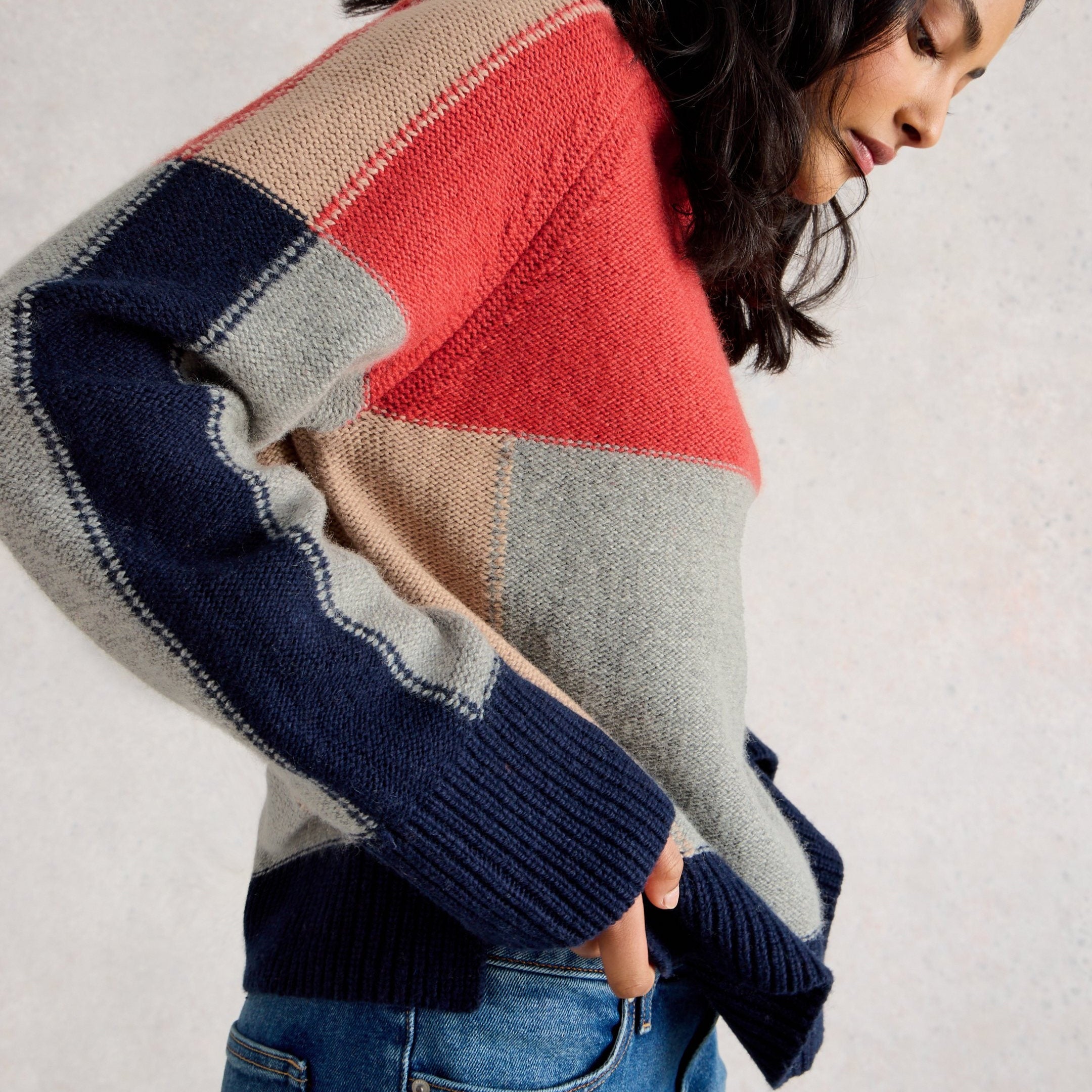 Person wearing a colorful patchwork sweater against a plain background