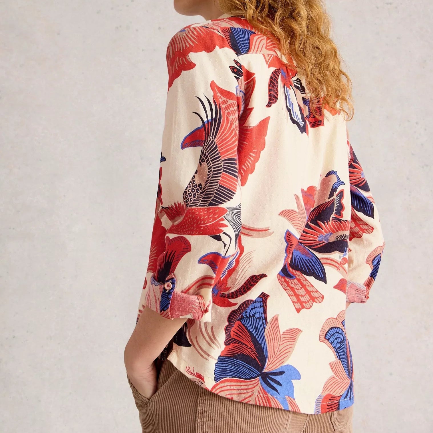 Woman wearing a colorful floral blouse with a plain background