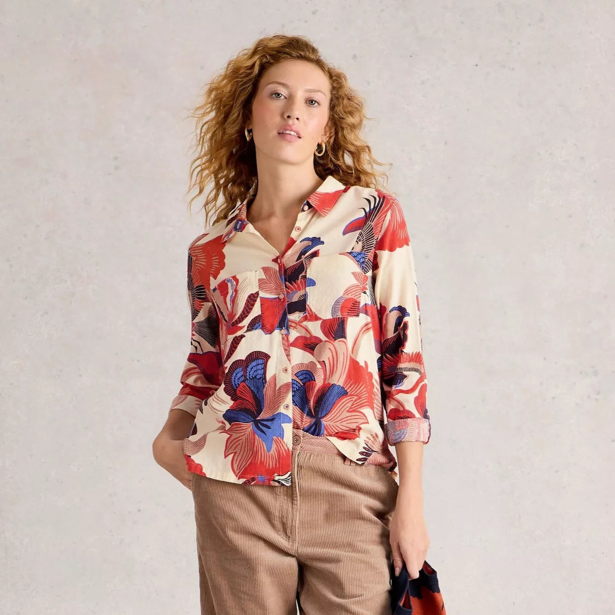 Woman wearing a colorful floral shirt against a plain background